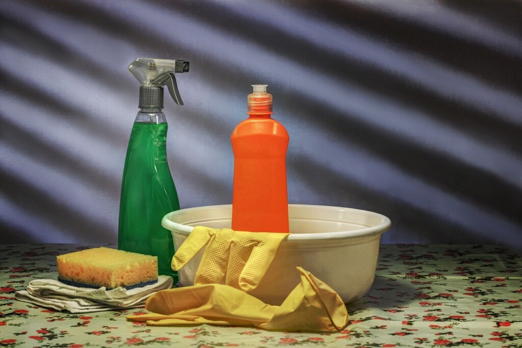chemical drain cleaner bottle next to rubber gloves and sink