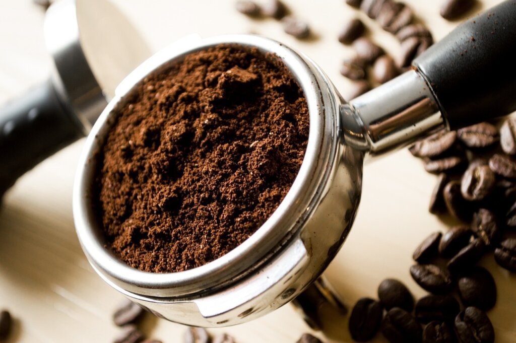 various uses of coffee grounds displayed on wooden kitchen counter