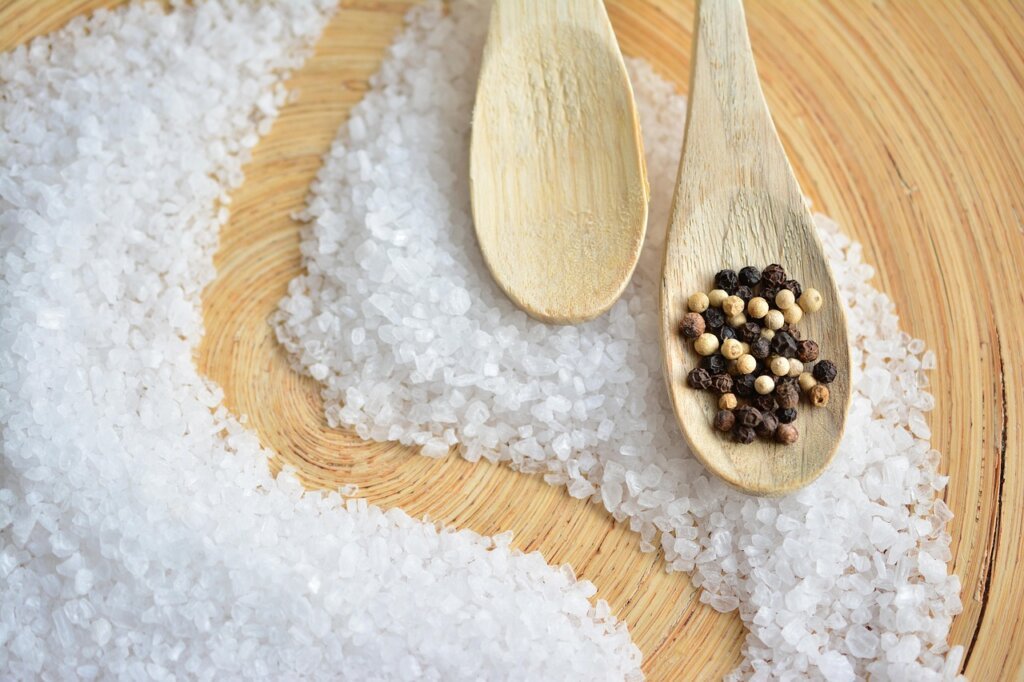 coarse salt being measured in a spoon over sink