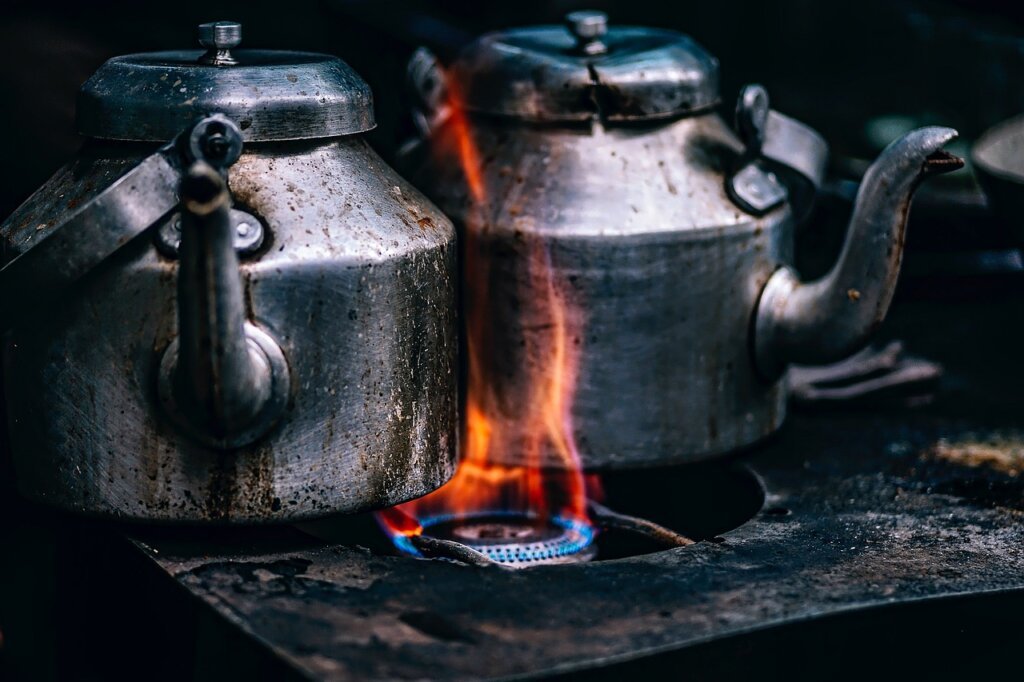 person wiping gas stove surface with damp cloth after cooking while stove is still warm