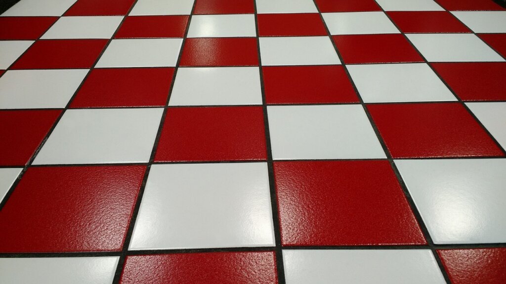grout sealer being applied to clean white kitchen tiles with small brush
