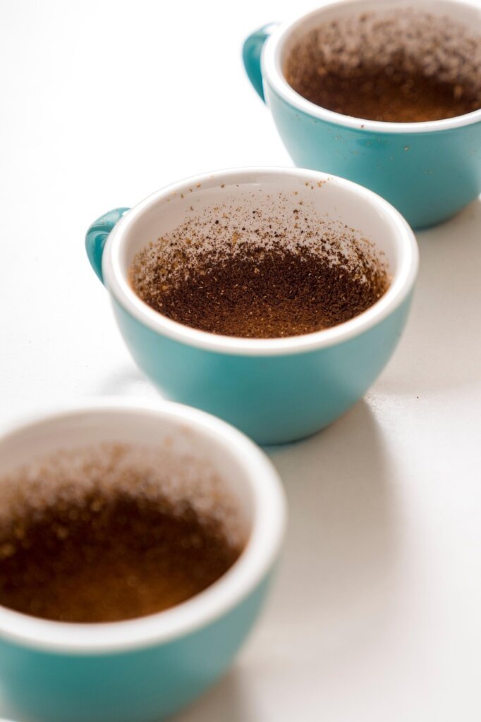 dried coffee grounds spread on white plate near refrigerator