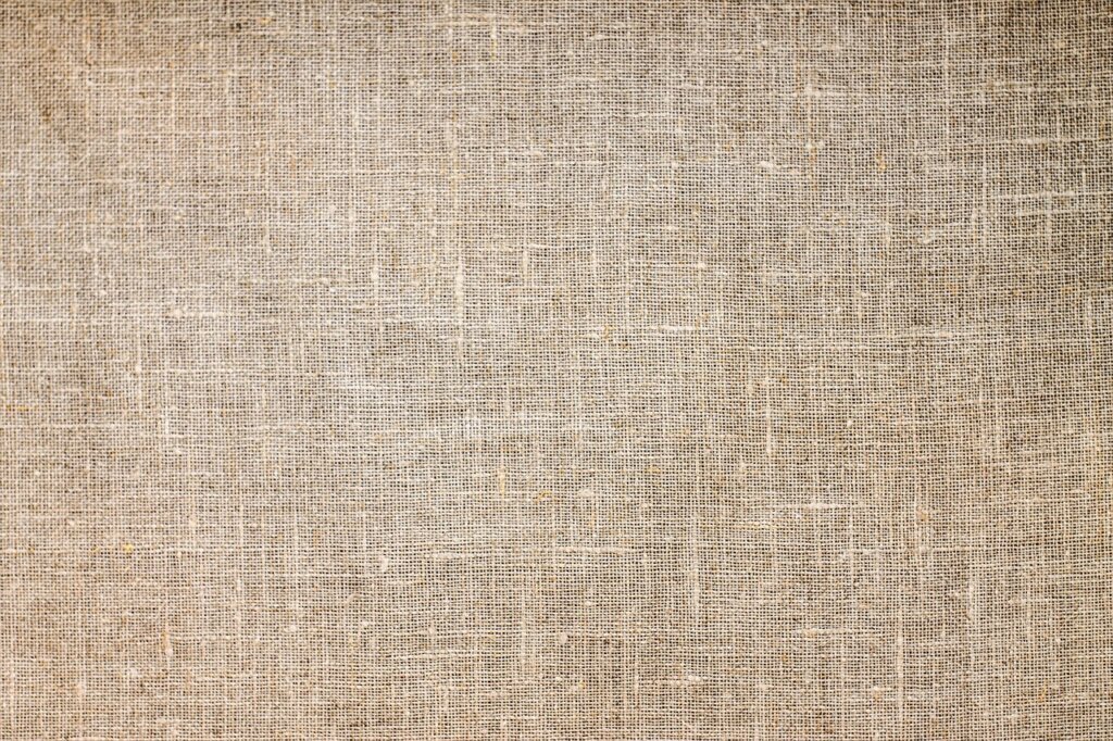 hand dabbing white microfiber cloth on beige fabric sofa to remove stain