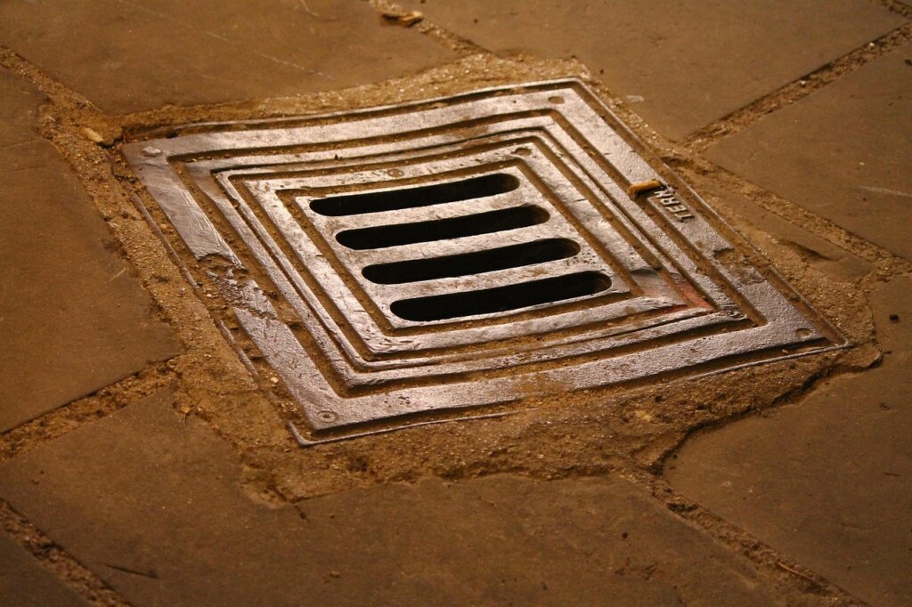 drain cleaning stick being inserted into a clogged floor drain